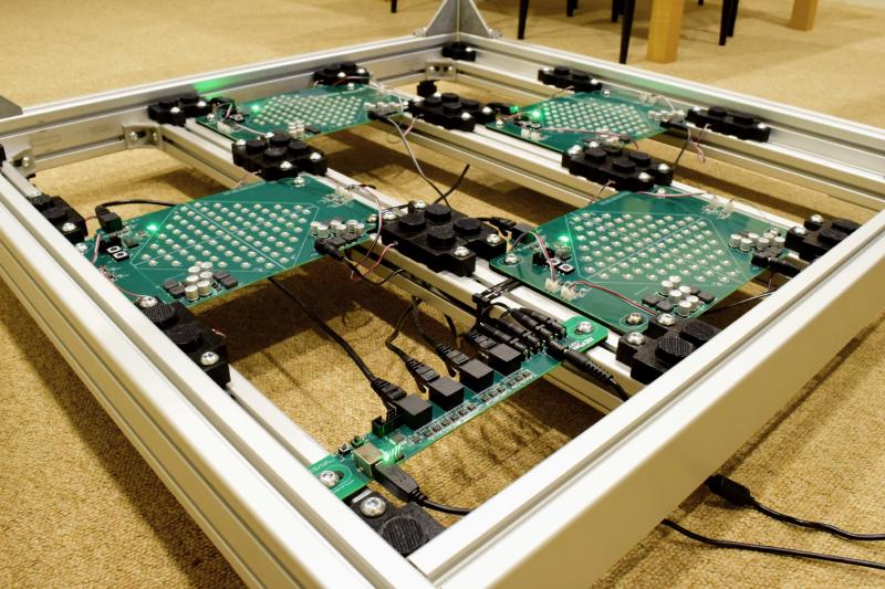 Lower angle view of the dance opened dance platform, showing a narrow PCB with 4 RJ-45 connector, 5 barrel-jack connectors, one USB connector nearby, and 4 boards with a lot of LEDs each further in background