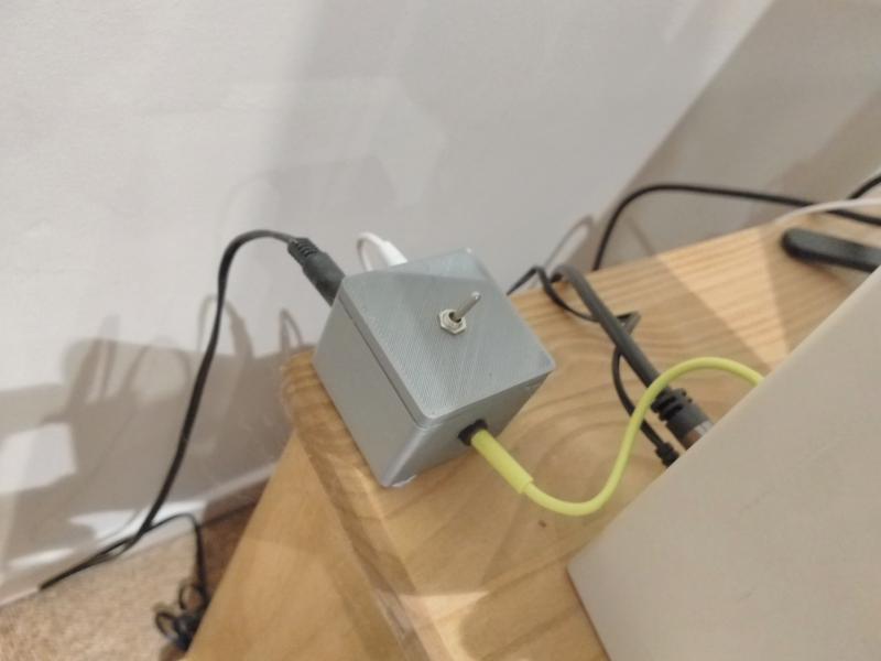 Rounded cube 3D-printed box with 3 cables protroduing from it, and a toggle switch on the top